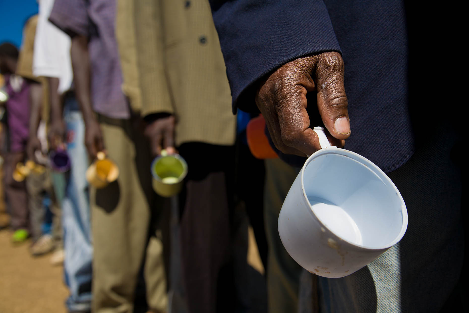 Men-wait-with-cups-at-humanitarian-aid-station